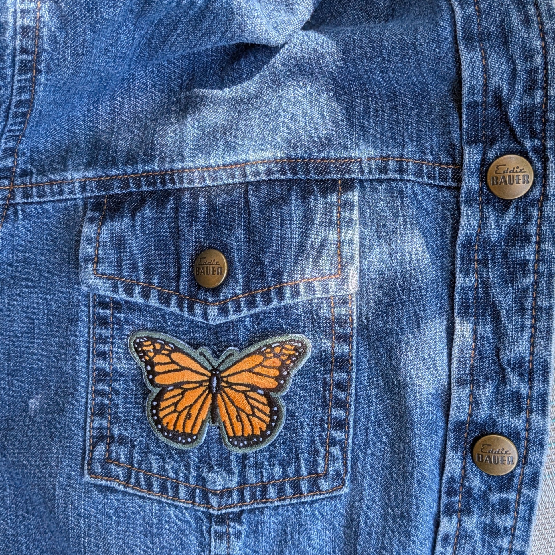 Iron this stunning Monarch butterfly patch onto your favorite denim jacket for an instant conservation statement. Vibrant orange and black embroidered wings with a grey border — bold enough to turn heads, meaningful enough to start conversations. 2.5" wide. Iron-on application included.